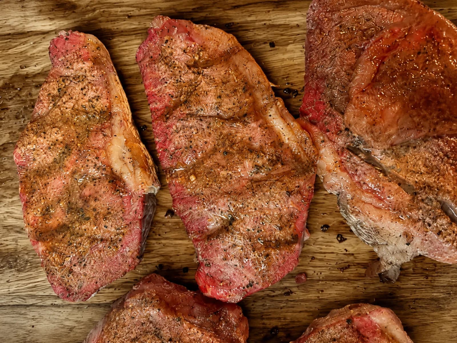 Seasoned ranch-raised steaks on a wood board from Salt Creek Legacy Meats